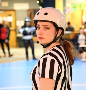 A roller derby referee makes resting ref face